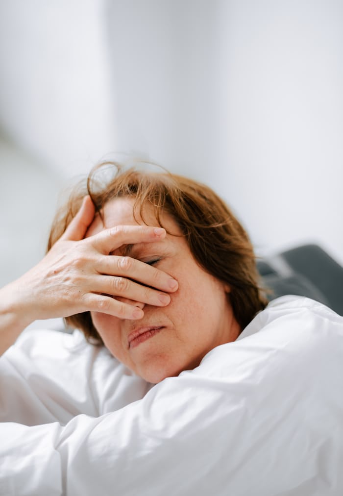 Woman resting with hands on head, monitoring for concussion vs serious brain injury symptoms