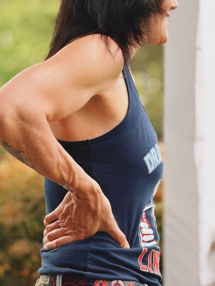 Office worker holding her back, illustrating whether sitting all day is causing your back pain