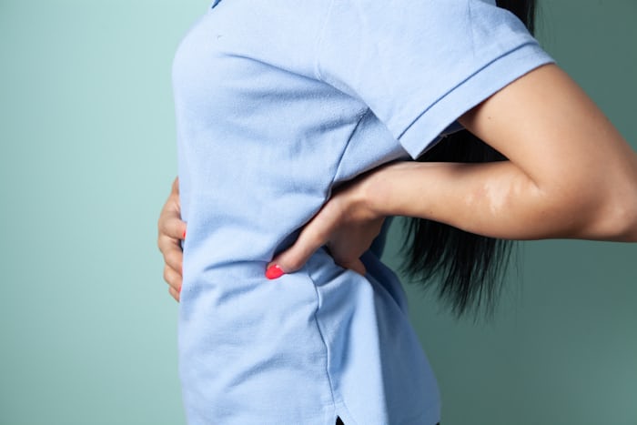 Woman holding her sore lower back, illustrating the sciatica vs slip disc distinction covered in this article
