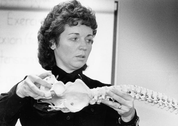 Doctor holding a human spine model to explain spinal fixation surgery