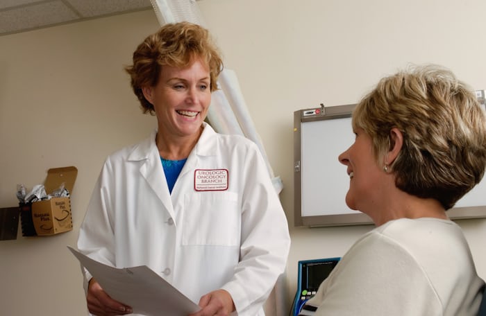 Smiling doctor in a white coat consulting with a patient, illustrating what does a neurosurgeon actually treat