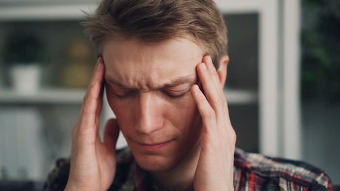 Man holding his temples with a morning headache, wondering is my headache a brain tumor